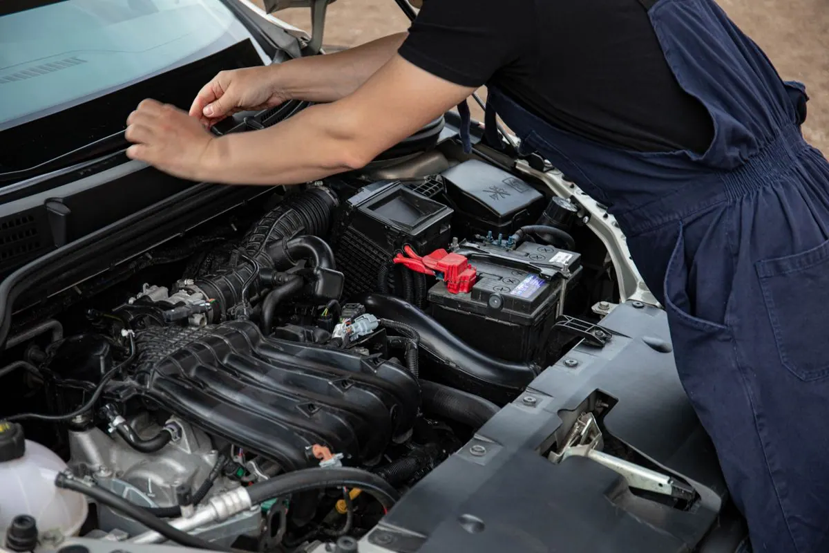 A mechanic working on a car engine outdoors